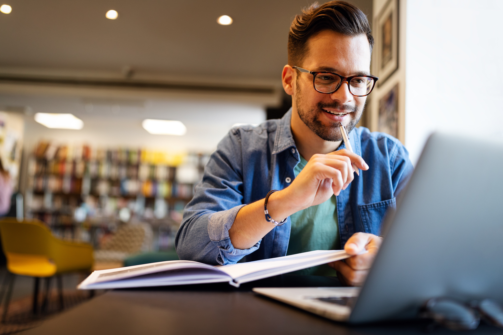 a man looking at a book with a pen researching facts behind drug and alcohol addiction